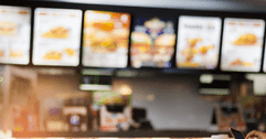Six blurry overhead menus hang in a fast food restaurant.  