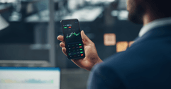 Man holding a phone showing a stock market chart