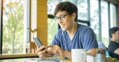 Man at coffee shop with cell phone and earbuds