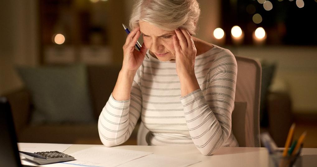 stressed senior woman filling tax form at home