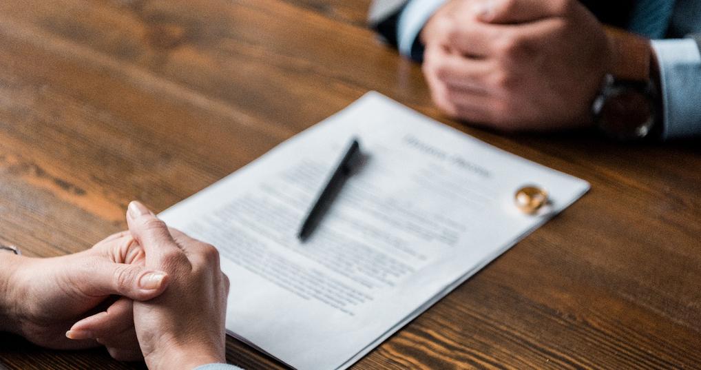  lawyer and client sitting at table with divorce decree and wedding rings