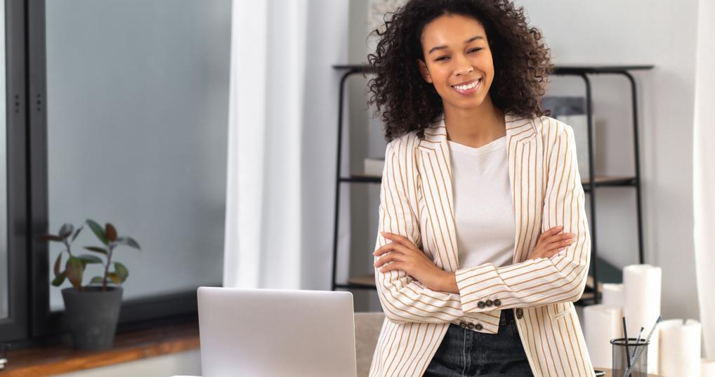 office worker stands with crossed arms near a desk