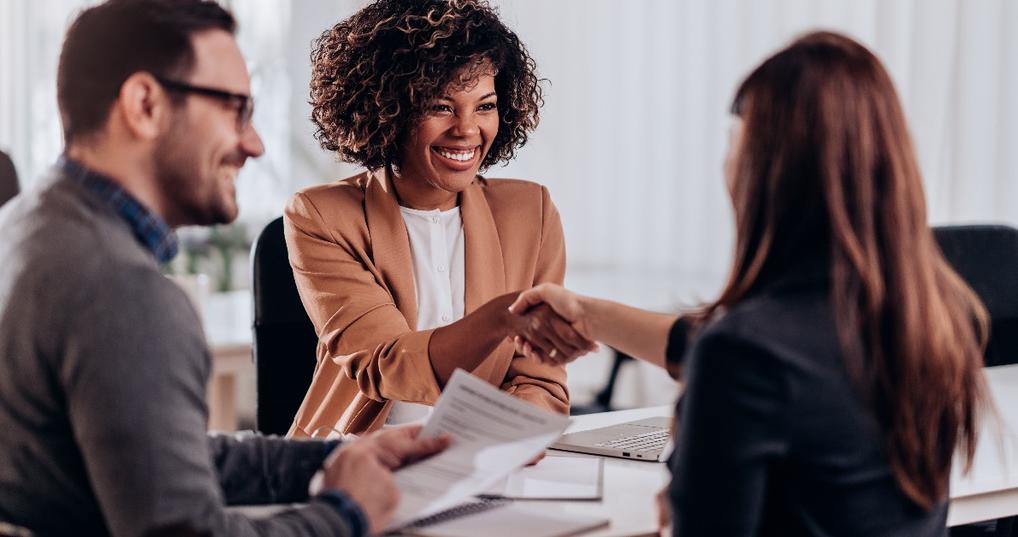 A female candidate receiving congratulations from a female interviewer after a successful job interview.
