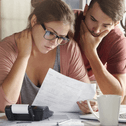 A concerned couple looks over their bills together. 