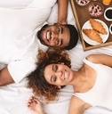 Couple enjoying hotel breakfast in bed