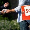 People shaking hands by 'sold' house sign