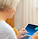 senior woman in her living room checking her investment portfolio on a tablet
