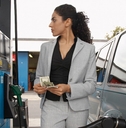 businesswoman counting money while looking on the meter of petrol pump