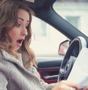 shocked woman in car reading insurance paper