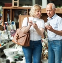 mature family couple choosing vintage dishes on street market