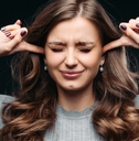 young beautiful woman closing eyes and blocking ears with fingers