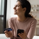 Smiling woman holding credit card and phone
