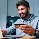 young man paying bills online with credit card and laptop
