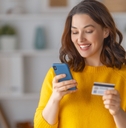 Very happy woman holding phone and credit card
