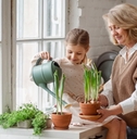 senior woman teaching young girl to care for potted plants