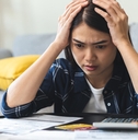 young woman stressed by calculating expenses on table