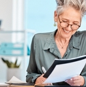 happy senior business woman sitting in office making notes while holding file