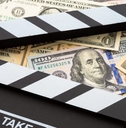 A movie clapboard on top of a pile of cash.