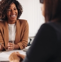 a female financial advisor with short curly hair is consulting a client with joy in her office setting.