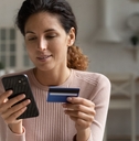 Smiling woman looking at phone and holding credit card