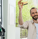 man holds credit card by gas pumps