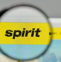 A magnifying glass hovering over the Spirit Airlines logo on the website homepage.
