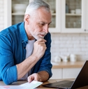 senior man reviewing taxes using laptop