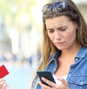 Woman with worried expression holding a credit card