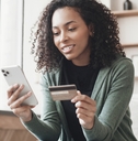 Woman looking at her phone and holding a credit card