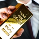 businessman holding 100g fine gold bar