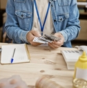 cluttered desk with bills, woman at desk crunching numbers