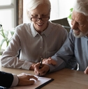 pensioners sitting at desk signing