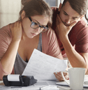 A concerned couple looks over their bills together. 