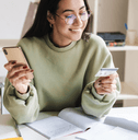 A woman smiles as she holds her phone and a credit card. 