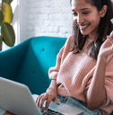 A woman sits on the couch with a laptop in her lap and holding a credit card.