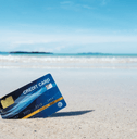 A credit card stuck in the sand on a beach.