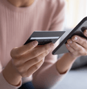 A woman holds her phone and credit card. 
