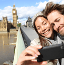 A woman and man smile together on a bridge while taking a picture.