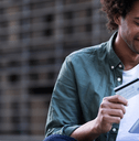 A smiling man holds a credit card and tablet.