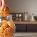 Woman taking oatmeal cookie from jar