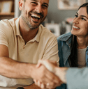 A man shakes hands with someone while his spouse smiles up at him.