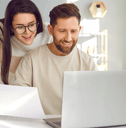 A man uses a laptop while a woman peers over his shoulder.