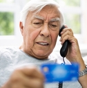 senior man calling while holding credit card