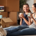 Young women sitting on floor of new home drinking coffee