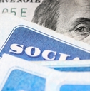 Dollar bill with Benjamin Franklin's eyes looking and Social Security cards