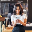 Person working at cafe using their mobile phone in front of the counter