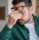 person rubbing eyes at desk