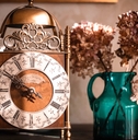 Old clock on the shelf next to flower vase
