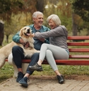 Older couple on a park bench with their dog