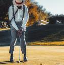 man wearing trousers with suspenders with a cigar in his mouth playing golf
